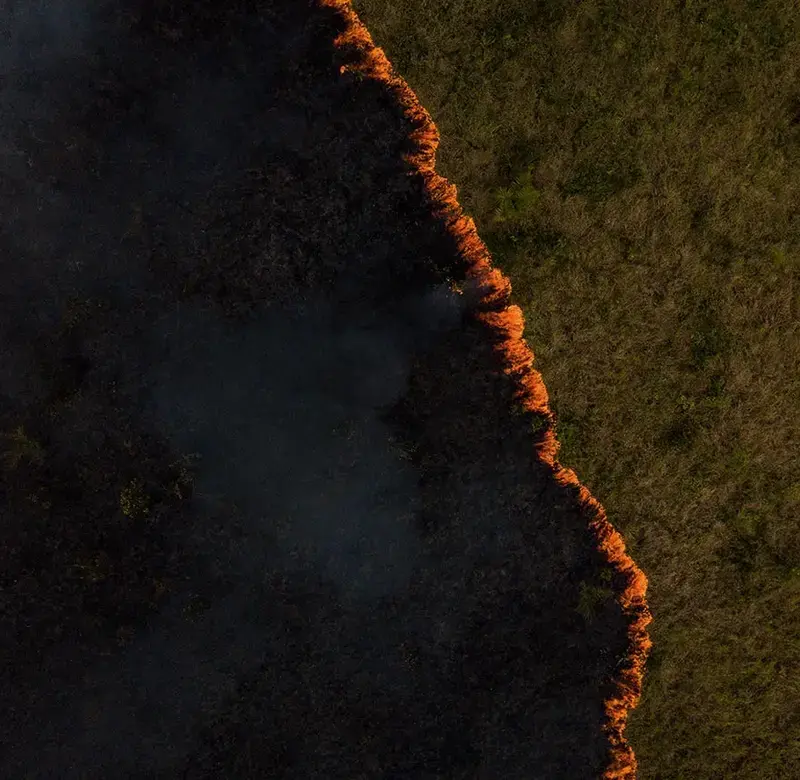 an aerial shot of a burning landscape with a line of orange fire down the photo
