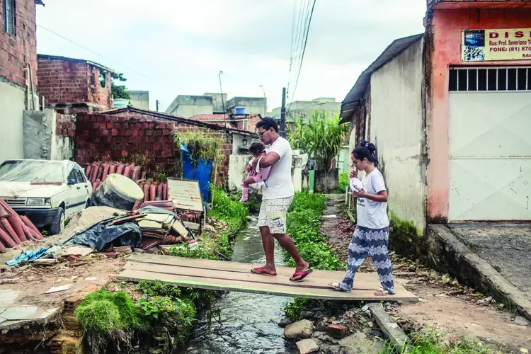 Nascimento e seu marido Luiz, atravessam um riacho aberto com sua filha, Valentina, voltando da casa dos avós de Dhulha.&nbsp;Fotografia por Fábio Erdos. Brazil, 2017.