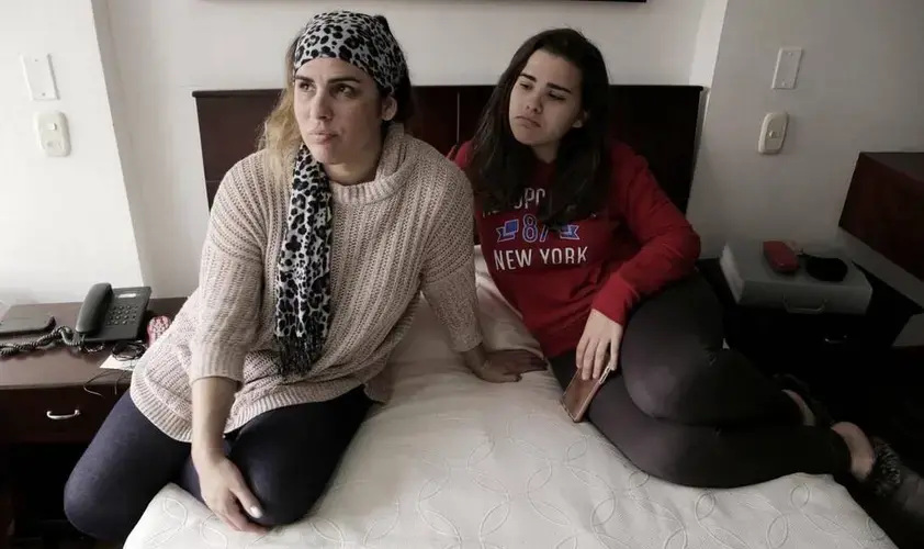 Lisset López Rodríguez (left) and her daughter Camila Guzmán López in their tiny hotel room in Bogota, Colombia as they wait for an interview date at the U.S. Embassy in Bogota. Since the reduction of staff at the U.S. Embassy in Havana because of health attacks against diplomats, Cubans that were in the process of getting permanent visas for their family members to travel to the United States now have to go to Bogota, Colombia to complete the process. Image by José A. Iglesias. Colombia, 2017.&nbsp;