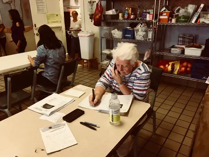 Sister Caroline Sweeney, a volunteer, calls relatives of the new arrivals to help them make travel plans. Most migrants leave Casa Vides after one night to join family or friends living elsewhere in the U.S.&nbsp;Image by Lily Moore-Eissenberg. United States, 2019.