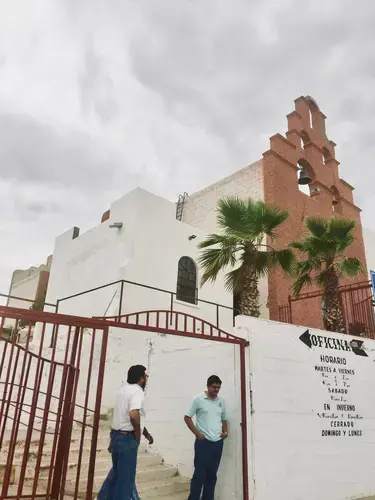 A priest talks with a friend outside his Juárez parish, which he has converted into a migrant shelter.&nbsp;Image by Lily Moore-Eissenberg. Mexico, 2019.