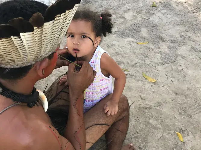 Mucunã (father) painting his daughter Micaela in preparation for a dance. Strong colors like black are reserved for times of battle and resistance among the Potiguaras of Catu. Image&nbsp;by Rafael Lima. Brazil, 2019.