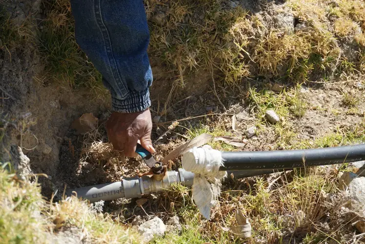 Gabino demonstrates the valve at the base of the reservoir.&nbsp;Image by Audrey Fromson. Peru, 2019.