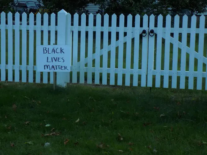 A Black Lives Matter sign in front of a Yarmouth resident’s white-picket fenced front yard. Image by Francesca Bentley. United States, 2020.