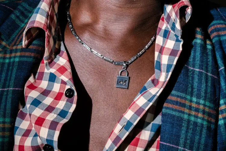 Sweet Love, a transgender woman and the chairperson of Children of the Sun, poses for a portrait with a necklace from her boyfriend. She sits at the Children of the Sun safe house, which shelters at-risk and in-need LGBTQ+ persons.&nbsp;Image by Jake Naughton. Uganda, 2017.