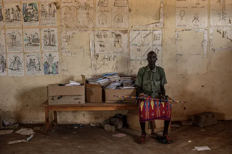 A young Rendille moran sits in a shuttered school building near the town of Laisamis in Kenya. Young men broke the windows of the school and have been living in the classrooms since the school was closed due to the COVID-19 pandemic.&nbsp;Image by Will Swanson. Kenya, 2020.