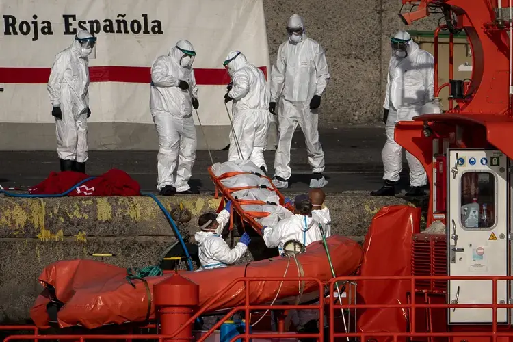 Emergency workers carry a migrant’s body after being found dead by the Spanish Maritime Rescue Service, at the Arguineguin port in Gran Canaria island, Spain, on Friday, Aug. 21, 2020. Image by&nbsp;Emilio Morenatti/AP Photo. Spain, 2020..jpeg