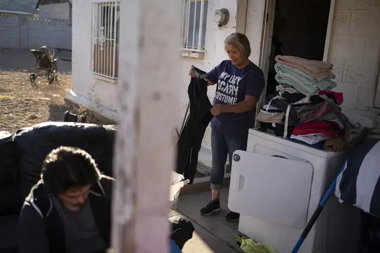 Norma Flores, 54, folds the laundry while her son works on his bicycle at their home in Henderson, Nev., Tuesday, Nov. 10, 2020. Image by Wong Maye-E / AP Photo. United States, 2020.