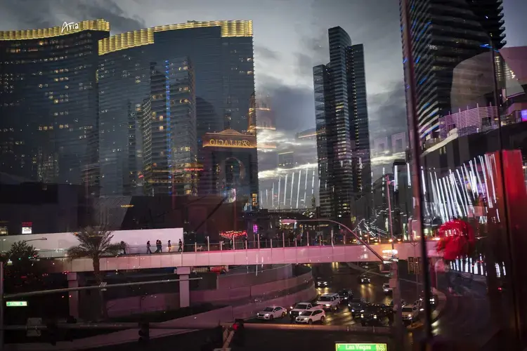 Casinos and other businesses are seen reflected in the glass walls of an overpass along the Las Vegas Strip. The coronavirus hit the Las Vegas economy particularly hard. Visitors to the area plummeted by more than 90 percent in a little over a month. The state's unemployment rocketed to 28 percent, the worst in the nation and a level not seen even during the Great Depression. Image by Wong Maye-E / AP Photo. United States, 2020.