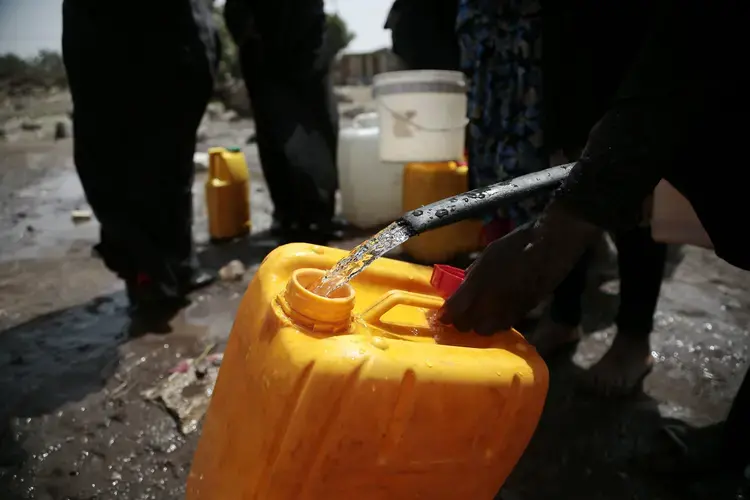 In this July 12, 2017 file photo, a woman fills a jerrycan with water from a well that is alleged to be contaminated with the bacterium Vibrio cholera, on the outskirts of Sanaa, Yemen. An Associated Press investigation finds that Yemen’s massive cholera epidemic was aggravated by corruption and official intransigence. The investigation has found that both the Iranian-backed Houthis rebels and their main adversary in the war—the U.S.—&nbsp;and Saudi-backed government that controls southern Yemen—impeded efforts by relief groups to stem the epidemic. Image by Hani Mohammed/AP. Yemen, 2017.