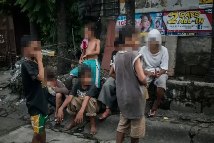 A group of young boys sniff glue on a street corner in Payatas, where many people make a living picking through rubbish for recyclable materials. The community has lost several young men to extrajudicial killings, and sniffing glue could lead to a death sentence (their faces have been obscured for their safety). One night earlier this month,&nbsp;32 people were killed&nbsp;as part of Duterte’s war on drugs. Image by James Whitlow Delano. Philippines, 2017.&nbsp;