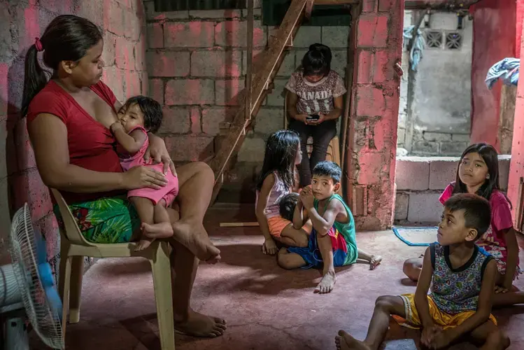 Roda, 29, has been left to look after six children, after her husband, Crisanto, a rubbish picker at the Payatas dump, was killed. Roda cannot work because she has an ulcerous infection on her thigh and also needs to look after the children. Some of the older kids are sent out to sell fried bananas and other street food to bring in a little money. Image by James Whitlow Delano. Philippines, 2017.