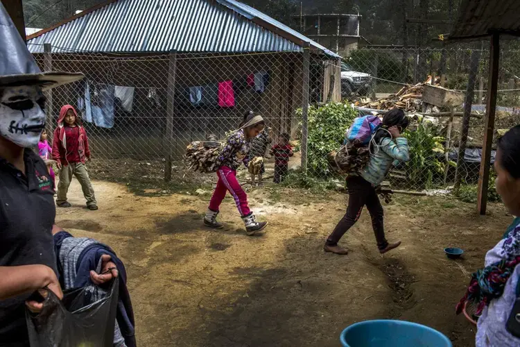 When men leave to find work in the United States, their tasks at home, like carrying wood, are left to wives and children, like these in Bulej, Guatemala. Image by Simone Dalmasso / For the Arizona Daily Star. Guatemala, 2019.