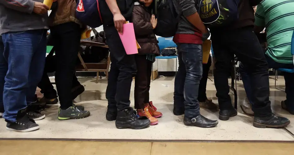 Migrants line up for help with phone calls and travel assistance as Tucson volunteers help hundreds of others with the basics of food, clothing, medical assistance and temporary shelter at a Tucson church. These migrants were among those that Customs and Border Protection dropped off after finding several large groups in the desert west of Tucson last October. Image by Mike Christy / Arizona Daily Star. Guatemala, 2019.<br />