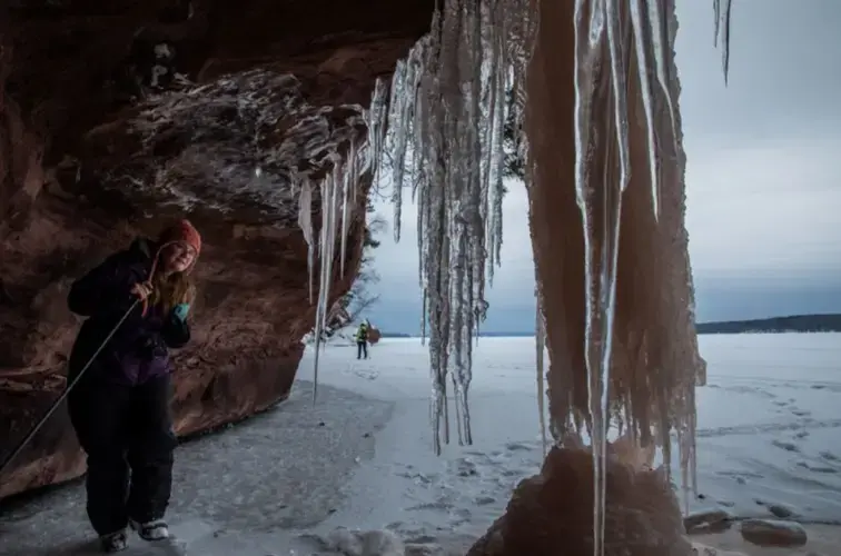 Rene Wagenaar, of Merrill, Wisconsin, examines ice formations during a tour of ice caves on the shore of Lake Superior in the Red Cliff reservation in Wisconsin on Feb. 15, 2020. Image by Zbigniew Bzdak/The&nbsp;Chicago Tribune. United States, 2020.