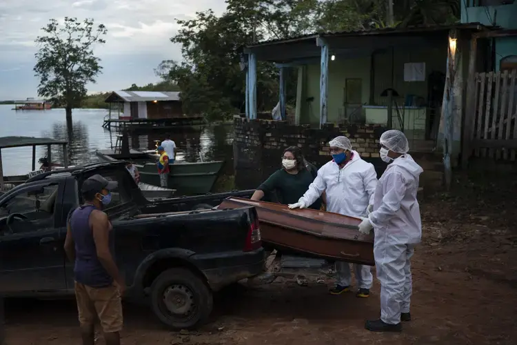 SOS Funeral workers move a coffin holding the body of an 86-year-old woman who lived by the Negro River and who is suspected of dying of COVID-19, near Manaus, Brazil, Thursday, May 14, 2020. Image by Felipe Dana / AP Photo. Brazil, 2020.