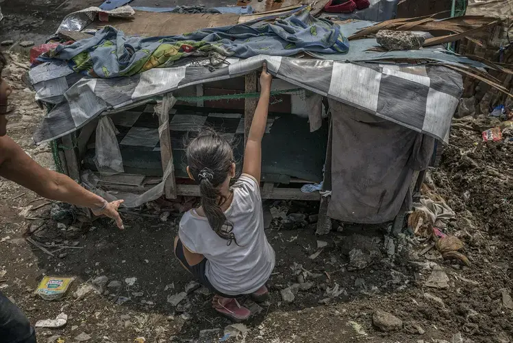After Sara’s husband Kulot was killed in Duterte’s War on Drugs, her home was burned down. Now, she lives in this former chicken coop in Navotas’s Market 3 slum. Her husband’s body was left in the morgue for over 25 days before being interred in a mass grave, because she could not afford a burial. Image by James Whitlow Delano. Philippines, 2017.