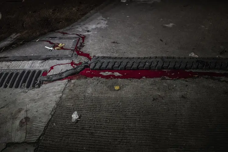 Manuel Borbe’s blood runs into a storm drain after he was killed by unidentified masked men on motorcycles in the Holy Spirit district of Quezon City. According to his sister, Vivian, Borbe dealt drugs, but not by choice; he was forced into the drug trade to support his addiction to methampetamines, known locally as shabu. Image by James Whitlow Delano. Philippines, 2017.