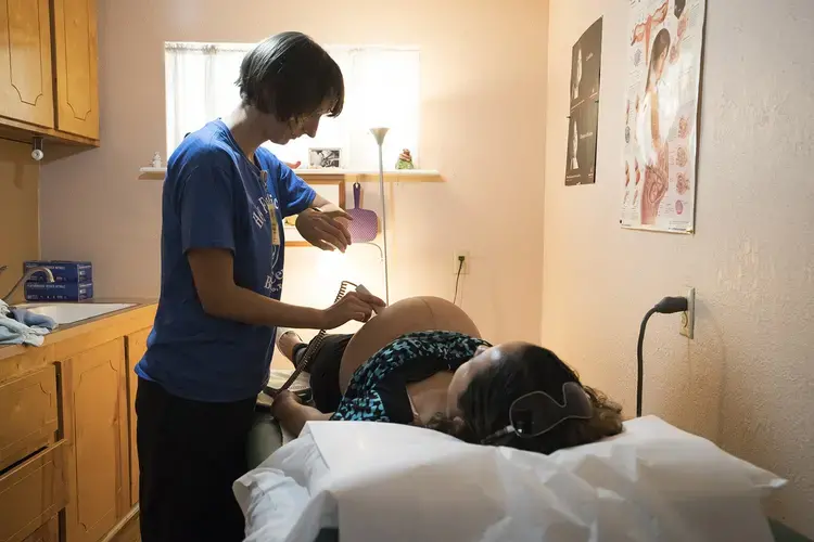 Vanna Waldron (left) evaluates Erika Piñon at the Holy Family Birthing Center in Weslaco, Texas. Waldron is a Certified Nurse Midwife from Seattle, Washington, who is volunteering at the birthing center for a year. Image by Reynaldo Leal for The Texas Tribune.&nbsp;​​​​​​​United States, 2018.&nbsp;