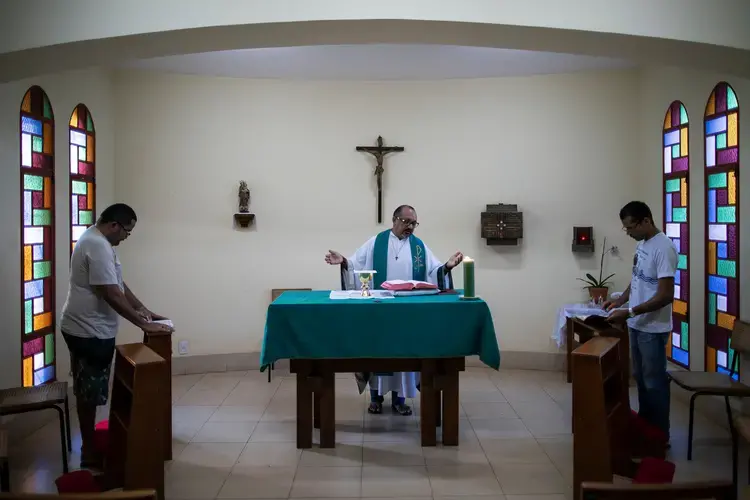 Father Amaro Lopes, center, celebrates a mass in a chapel at the bishop’s house in Altamira. Image by Spenser Heaps. Brazil, 2019.