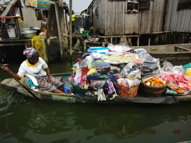 A woman paddles her merchandise on a canoe in Otodo Gbame. Image by Bukola Adebayo. Nigeria, 2017.<br />