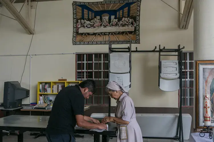 A nun helps a patient with his medication at the Our Lady of Guadalupe Migrant Home in Reynosa,&nbsp;Mexico, on May 2, 2017. According to the director of the shelter, the majority of the people staying at the shelter are recent deportees from the United States.&nbsp;Image by Meghan Dhaliwal. Mexico, 2017.