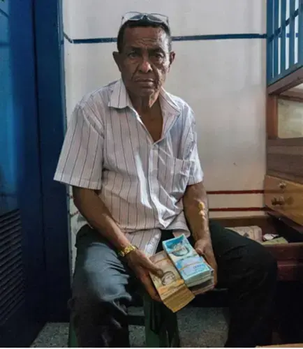 The owner of a local gold pawn shop in Tumeremo, Bolivar state, shows a stack of Venezuelan money, worth only a few dollars due to the nation’s rapidly escalating inflation. Image by Bram Ebus. Venezuela, 2017.<br />