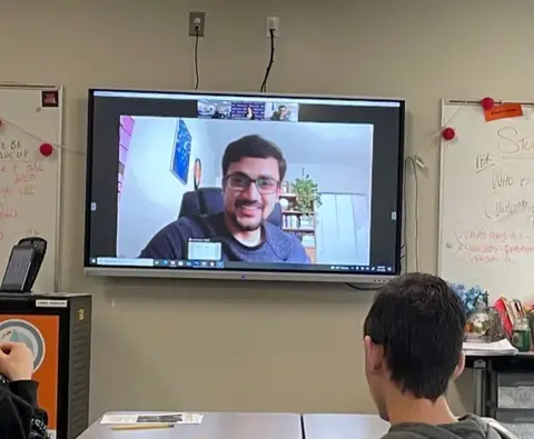 High school students face a screen where journalist Imran Mohammad Fazal Hoque presents on his reporting about Rohingya refugees