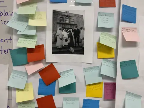 A Black and White photo of the Bronzeville neighborhood on a giant post-it and surrounded by small multicolor post its with student reflections on the image