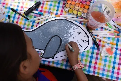 A child colors a picture of a dugong