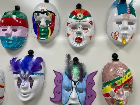 Seven student masks hang on a wall.