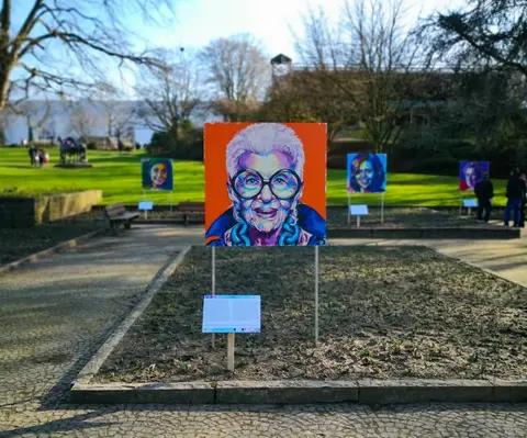 A colorful portrait in an outdoor exhibit. Other portraits are visible in the background.