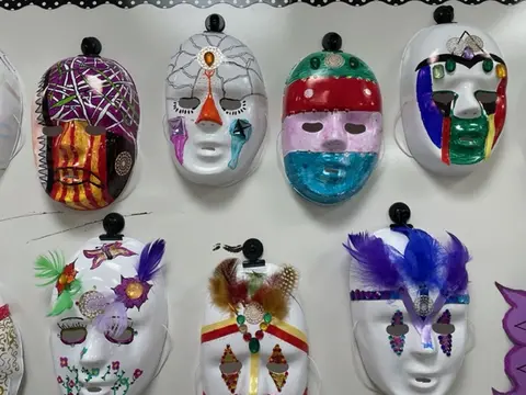 Eight student masks hang on a wall.