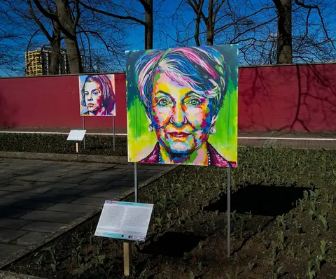 A colorful portrait in an outdoor exhibit. There is another portrait in the background.