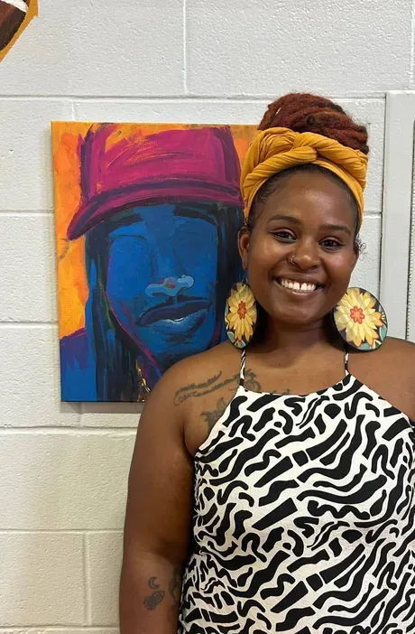 a woman poses in front of her painting