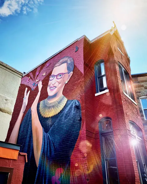 A mural of Ruth Bader Ginsburg on the side of a red brick building.