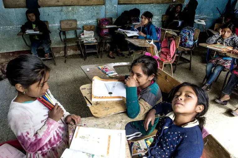 An empty desk where Baldemar Lucas García Alonzo once sat sits against the wall at the primary school in Bulej, Guatemala. Baldemar left with his father the previous week for the U.S. Image by Simone Dalmasso / The Arizona Daily Star. Guatemala, 2019. 