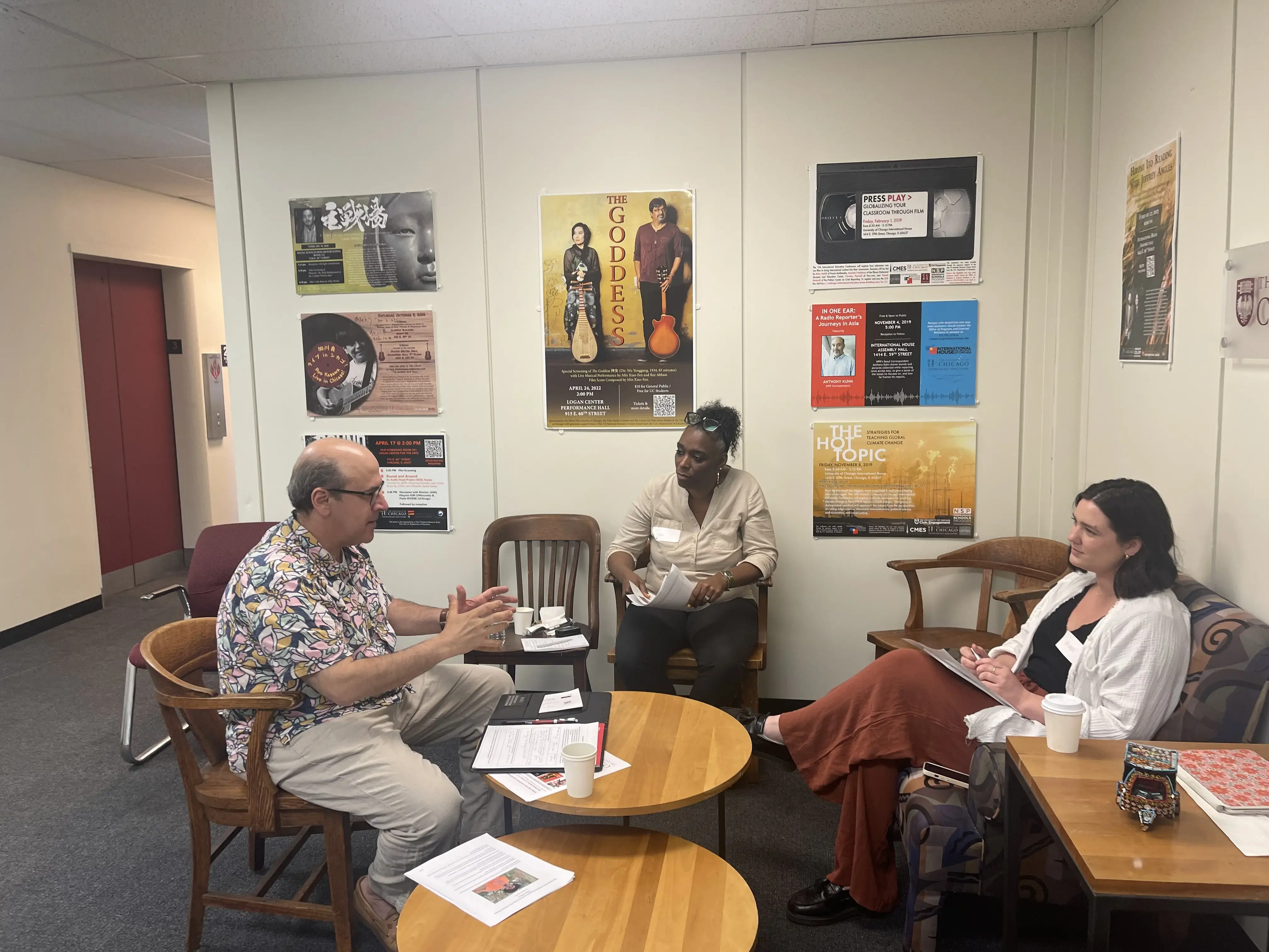 Three educators (two female and one male) sit around a table and discuss an article
