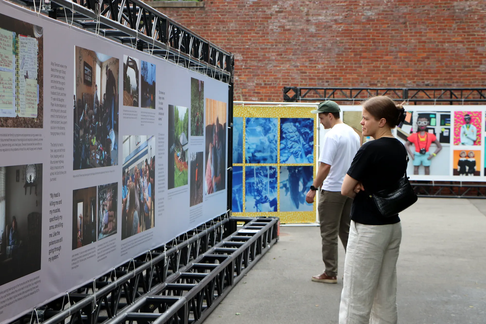 Woman in black shirt stands and looks at photos in banner. 