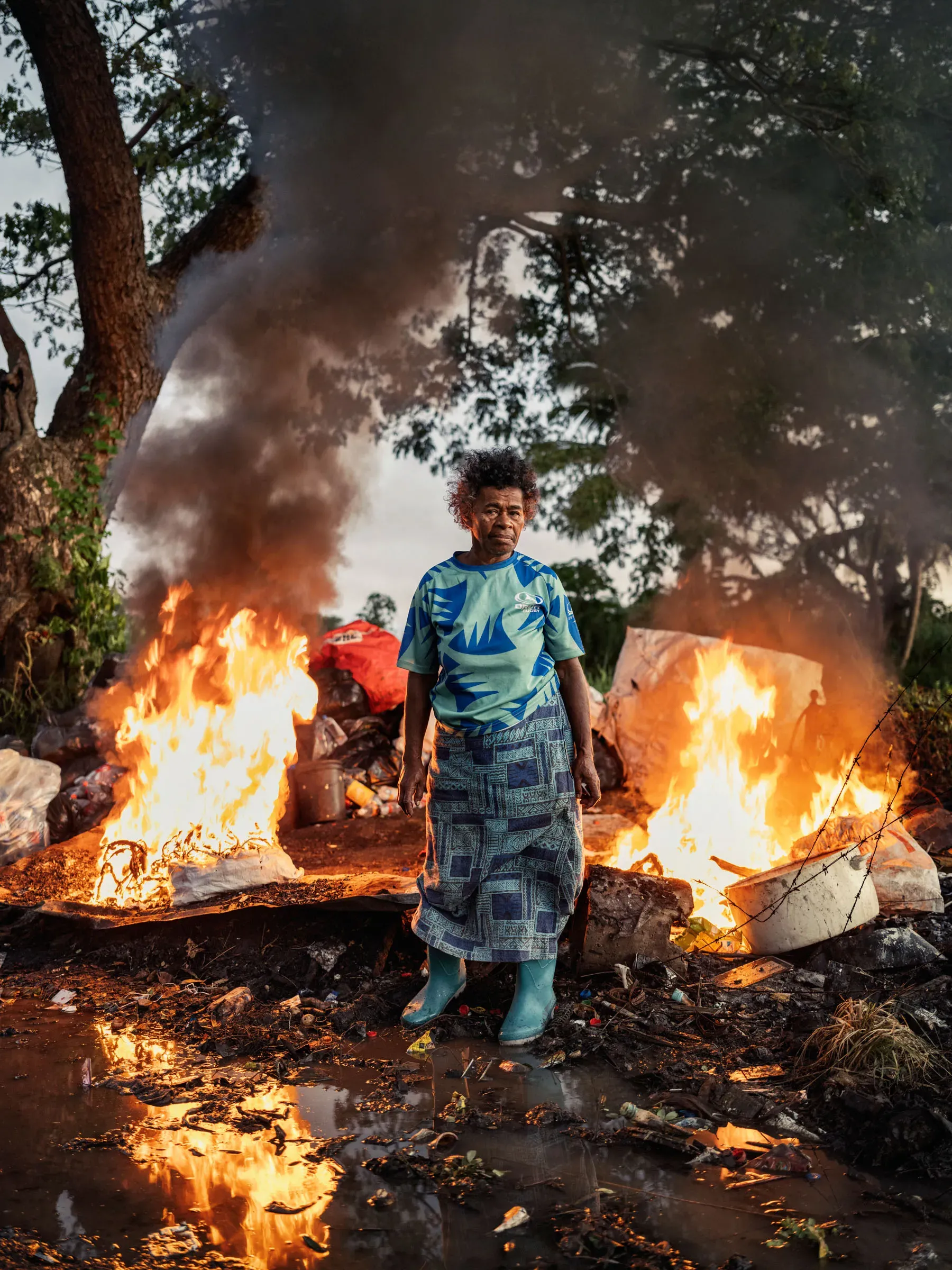 Asinate Lewabeka—a woman who makes an income washing and sorting cans, plastic bottles, and other materials for recycling—burns trash near her home in Lautoka, Fiji, on May 9, 2024