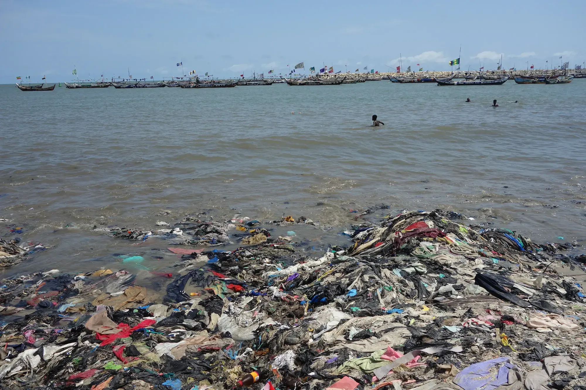 A surplus of secondhand clothes end up littering and contaminating Ghana's beaches and waters. Image by Anne Whiting. 2023.