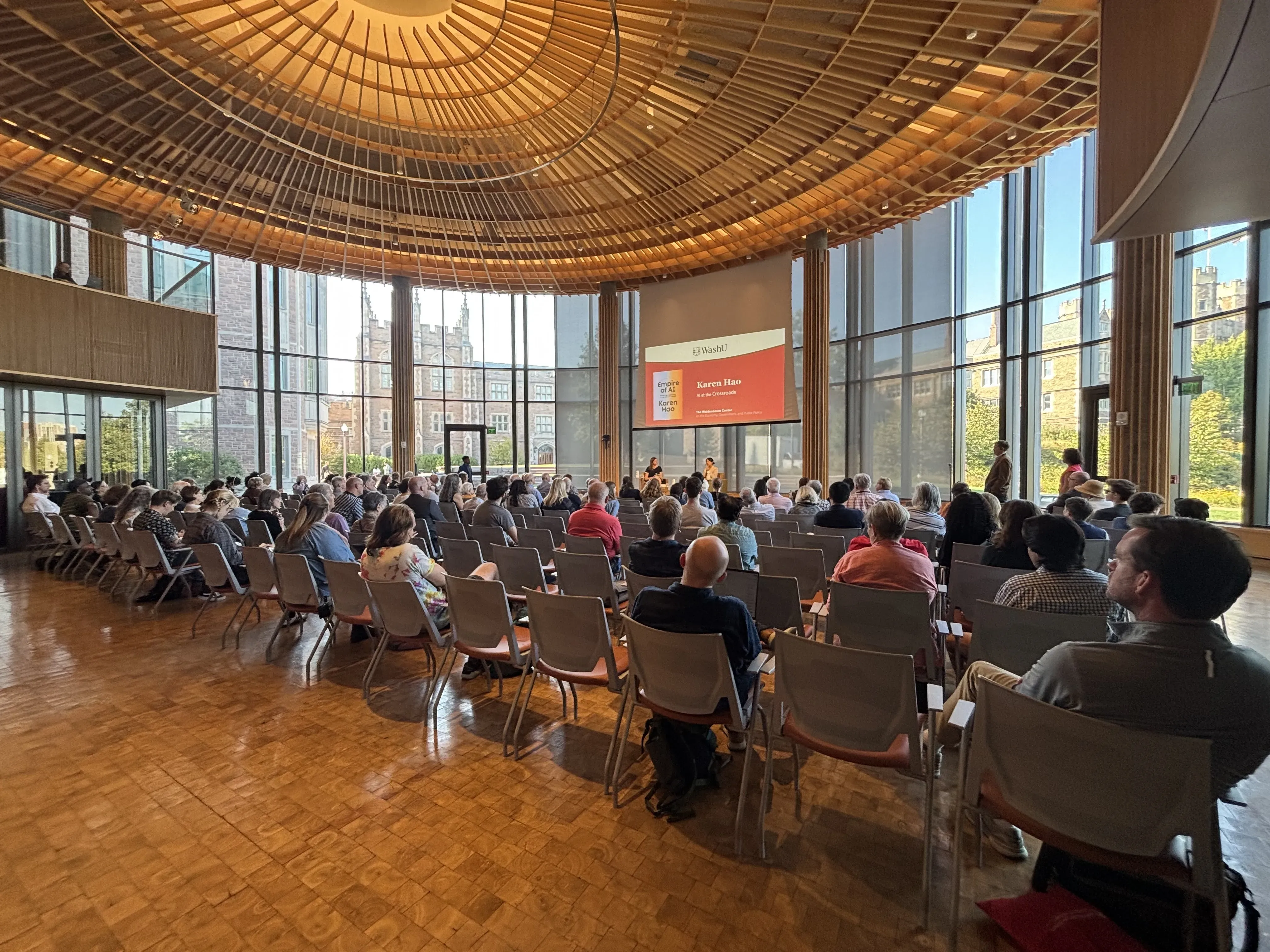 people gather in a large conference room to attend a panel