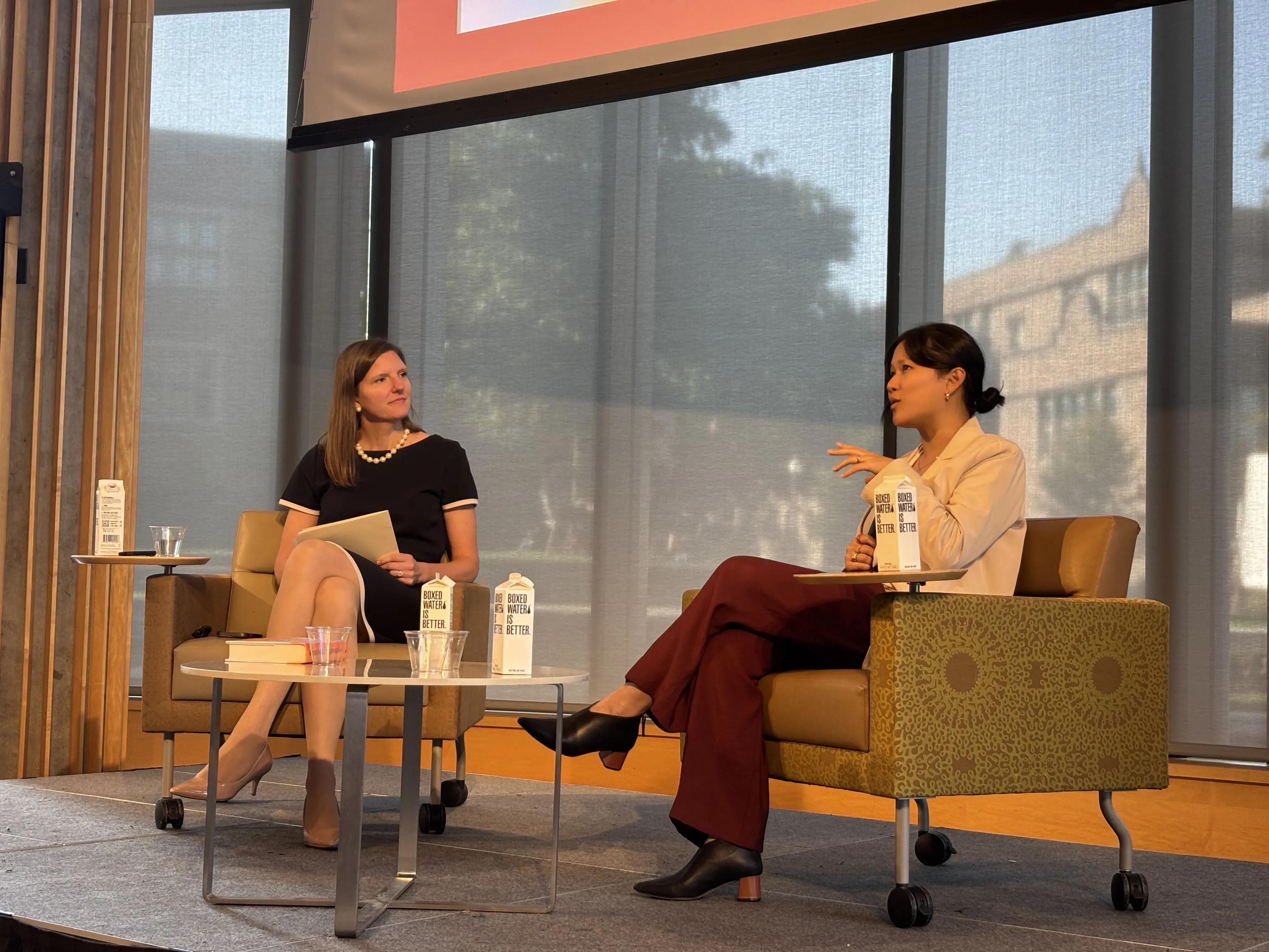 Two women speak on a platform
