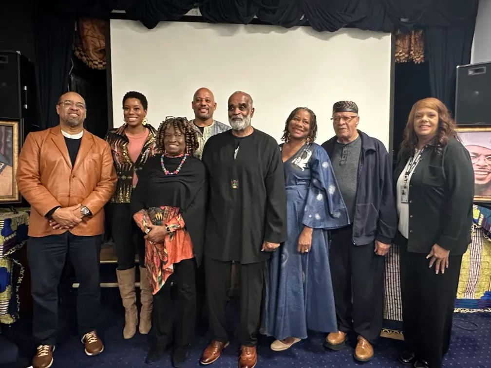 Veronica stands with presenters participating in The Ink and The Iron Event. 8 Black educators and community leaders stand together smiling at the camera.