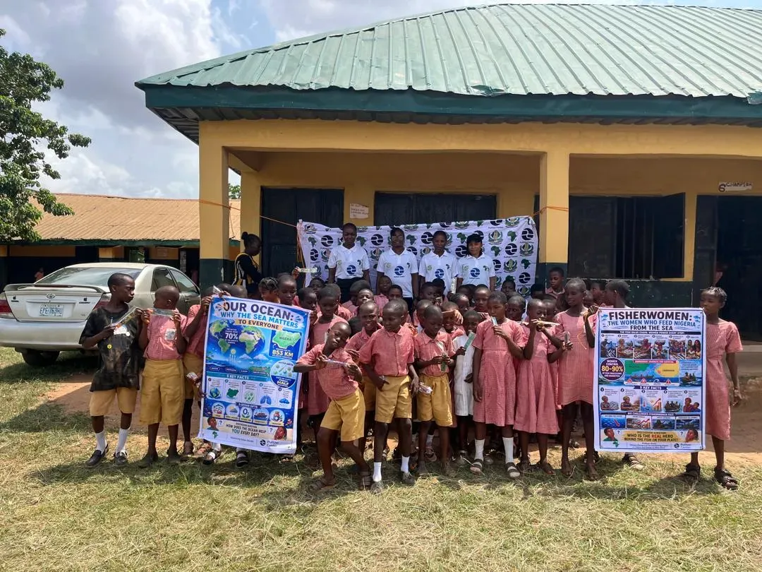 a classroom of kids poses with educational posters 