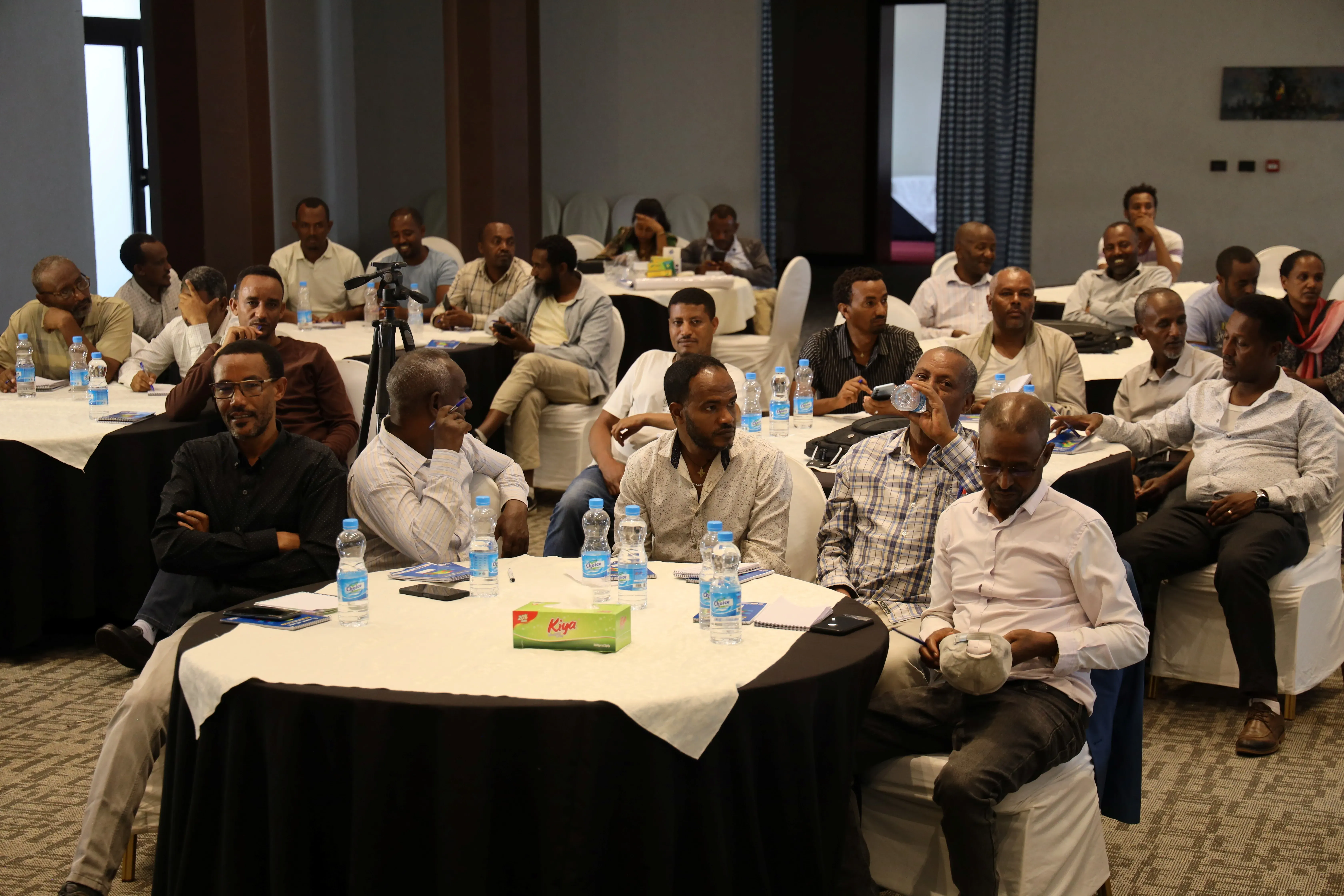 Participants sit at tables during the hybrid workshop and webinar in Addis Ababa.