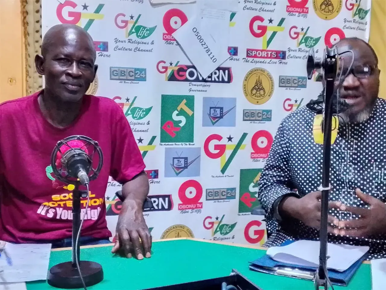 two men sit to host a radio show with microphones