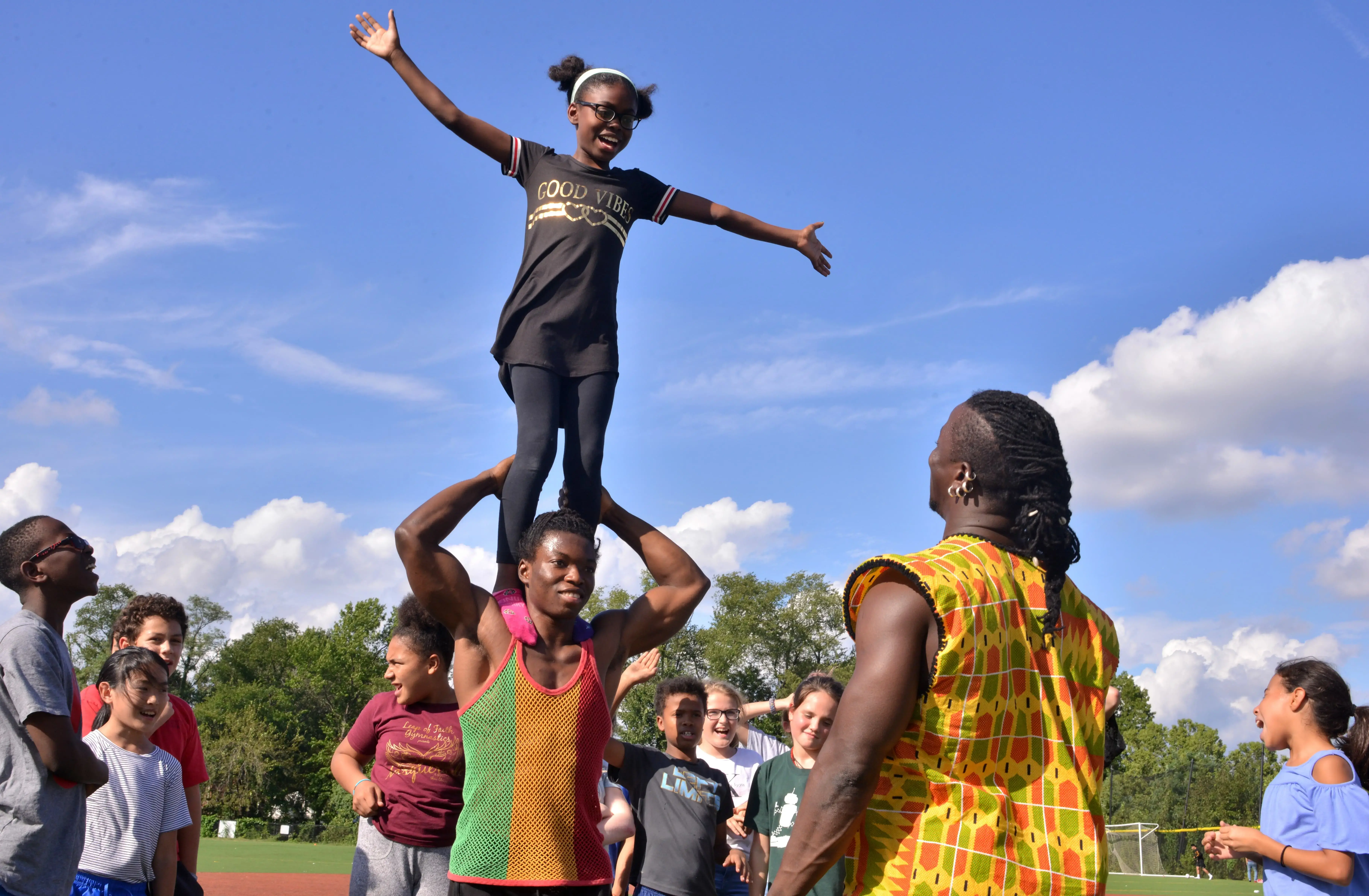 A Deal Middle School sixth grader balances on the shoulders of a Circus Kalabanté acrobat. Image by Dermot Tatlow. United States, 2018.