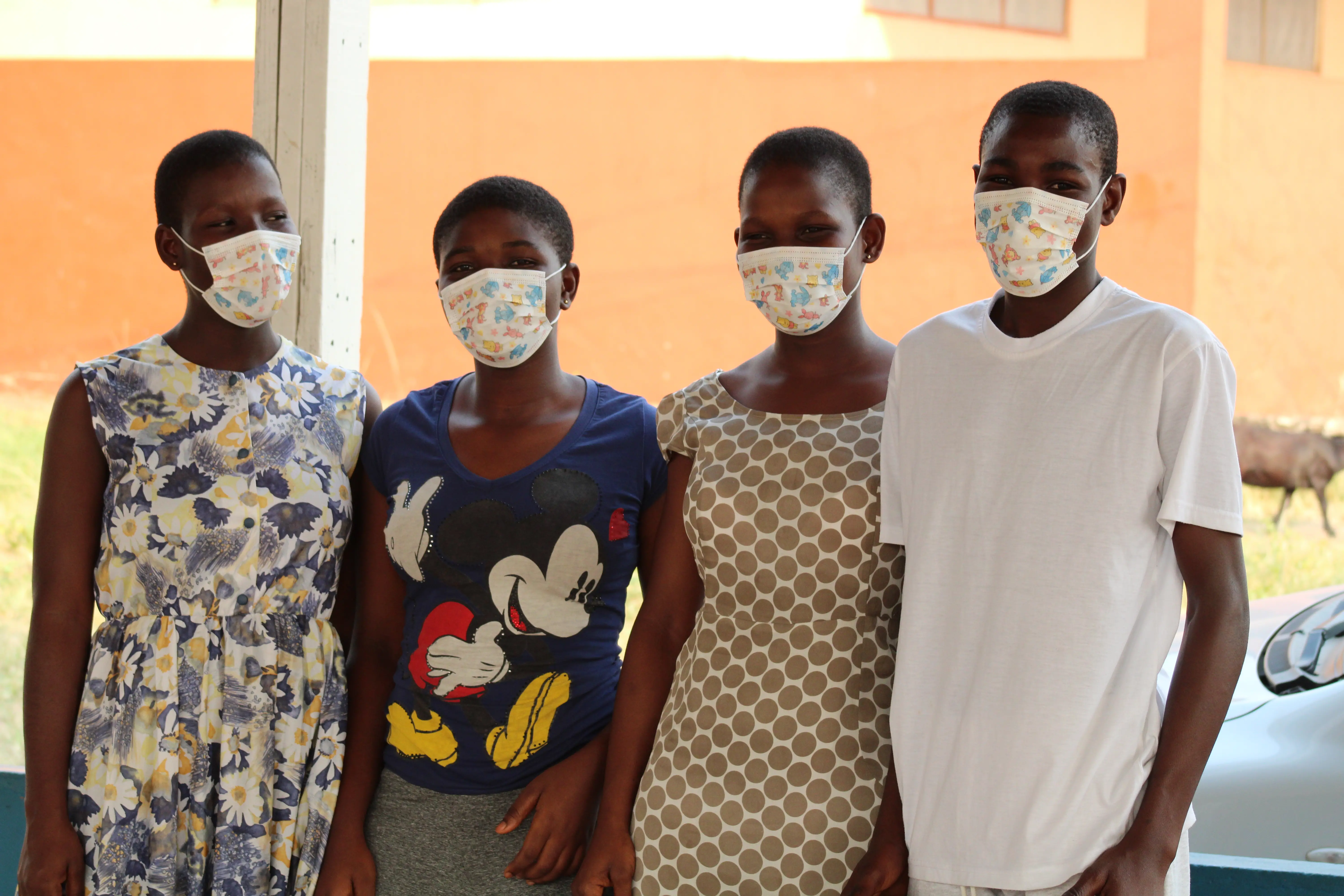 Teenagers at Haven of Hope wear matching face masks as they sit outside after school. 