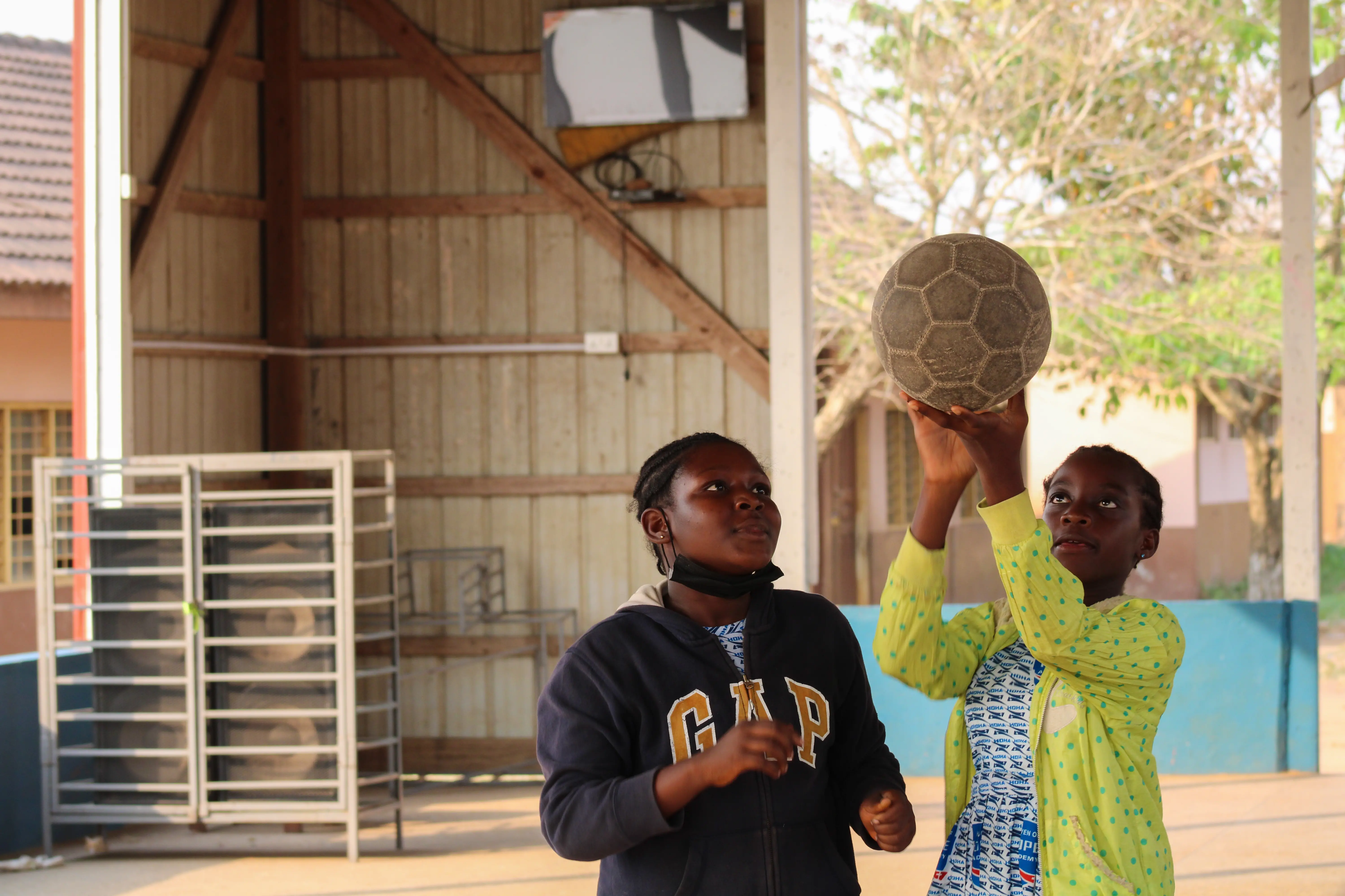 Two girls play basketball with a soccer ball at Haven of Hope’s outdoor recreation area.